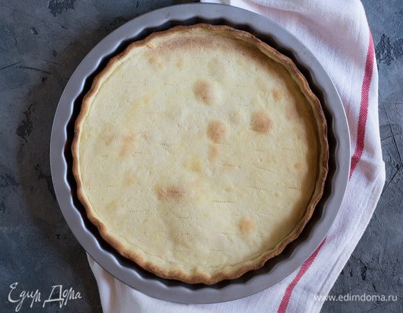 Разогрейте духовку до 180°С. Уложите поверх теста бумагу для выпечки и насыпьте керамические бобы или сухой рис. Уберите в духовку на 10 минут, затем достаньте и уберите бумагу с рисом. Поставьте форму обратно в духовку еще на 10 минут. Остудите.