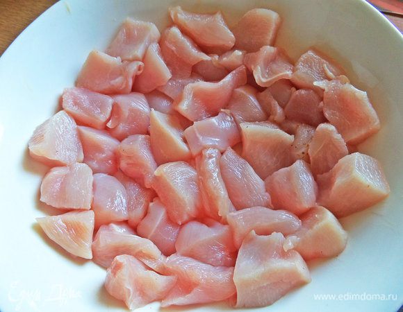 Заранее замариновать курицу. Для этого филе нарезать кубиками.