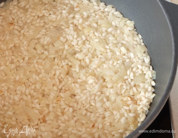 Затем вливаем вино. Когда вино почти испарится, вливаем первый половник куриного бульона. Перемешивать рис нельзя, просто аккуратно разравнивать лопаткой.