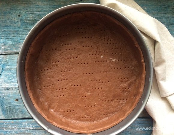 Разогрейте духовку до 200°С. Раскатайте тесто на присыпанной мукой поверхности в круглый пласт диаметром 30 см и толщиной 5 мм. Переложите тесто в форму диаметром 23 см и разровняйте по дну и стенкам. На дне тесто наколите вилкой в нескольких местах и уберите в холодильник на 20 минут.