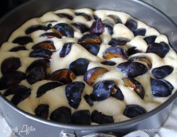 Форму застелить пергаментом (у меня 26 см), выложить тесто и затыкать его половинками слив.
В духовку (190°С) на 40 — 50 минут (до готовности).