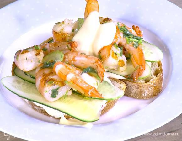 Подсушенный хлеб смазать майонезом с йогуртом, выложить полоски огурца и креветки, еще немного полить все майонезом с йогуртом.
