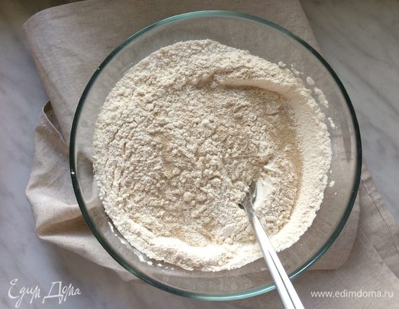 В большой миске смешайте просеянную муку с дрожжами, так чтобы дрожжи распределись равномерно.
