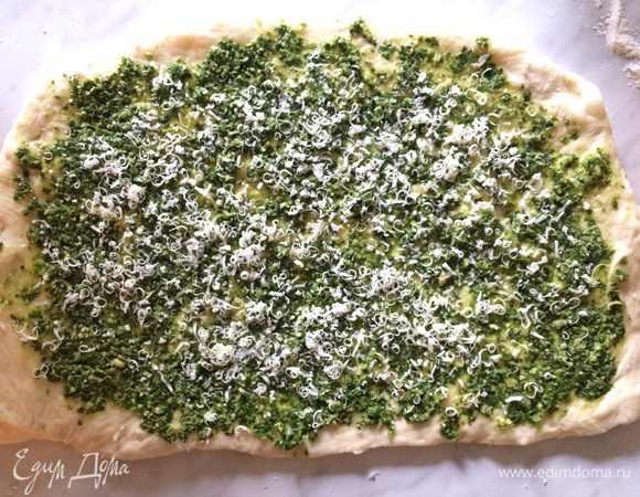 Раскатайте тесто на присыпанной мукой поверхности в прямоугольный пласт размером 10 на 15 см. Смажьте соусом песто и посыпьте тертым пармезаном, оставив по 1 см с каждой стороны.