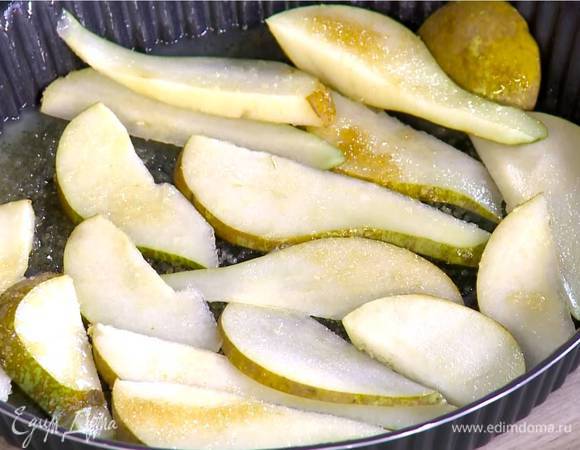 В форму для выпечки влить оставшееся растопленное масло, посыпать оставшимся сахаром и плотным слоем выложить половину груш.