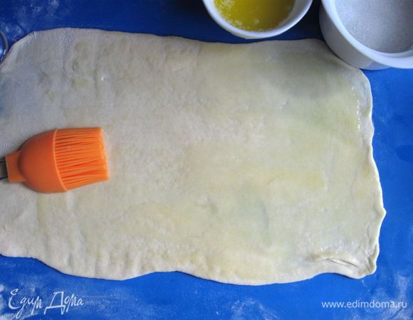 Раскатать каждый шар, придав каждому куску теста форму прямоугольника. 
Смазать первый кусок теста кисточкой  растопленным маслом, смешанным с лимонным соком. 

