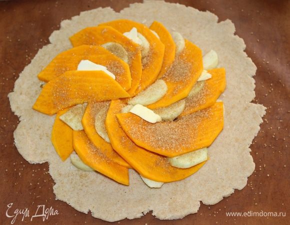 Тесто раскатать, выложить на него тыкву, нарезанную тонкими пластинками, дольки яблока, кусочки сливочного масла. Посыпать сахаром.