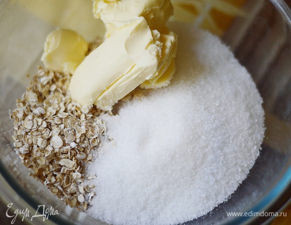 Теперь готовим овсяное тесто. В глубокой миске смешиваем овсяные хлопья, сахар, щепотку соли, охлажденное сливочное масло и муку. Обычный сахар здесь можно заменить коричневым, вкус только улучшится.
