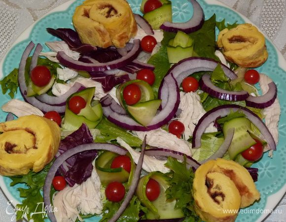 Добавить черри. Омлетный рулет разрезать на кусочки шириной около 2 см и выложить сверху салата.