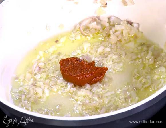 Чеснок почистить, мелко порубить, отправить к луку и все слегка обжарить, затем добавить томатную пасту и перемешать.