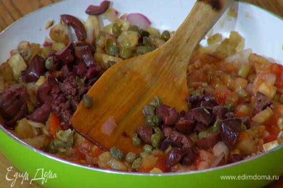 В сковороду с овощами добавить оливки, каперсы, измельченный тархун и все перемешать.