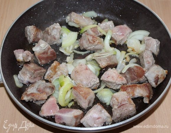 Свинину нарезать небольшими кусочками, обжарить 4 — 5 минуты до золотистой корочки. Добавить нарезанный полукольцами лук и измельченный чеснок, обжариваем.