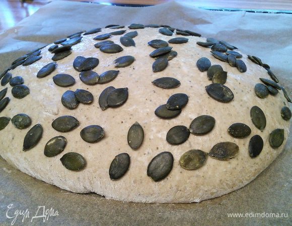 После 2 часов расстойки тесто выложить на посыпанную мукой поверхность, сформировать буханку, перенести «швом» вниз на противень, покрытый пекарской бумагой. Смазать водой и посыпать семечками. Накрыть какой-нибудь объемной крышкой, чтобы тесто не обветривалось, и оставить на отдых в теплой духовке на 1,5 часа. 