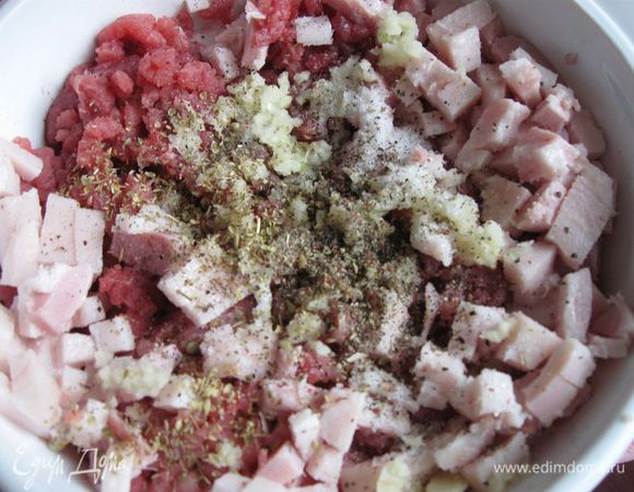 В фарш добавить чеснок, грудинку, каперсы, сушеный орегано, соль, свежемолотый перец.