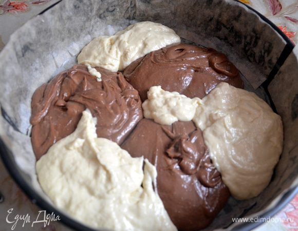 Форму для выпечки смазать сливочным маслом и простелить пекарской бумагой. Ложками по очереди выложить в форму тесто.