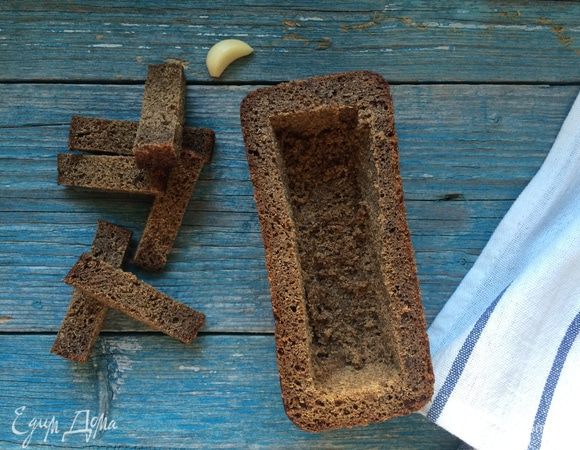 Разогрейте духовку до 100°С.
Срежьте у буханок хлеба верхушки и аккуратно удалите мякиш, стараясь не повредить дно и стенки. Смажьте буханки изнутри чесноком и сливочным маслом и уберите в духовку на 15 минут.
