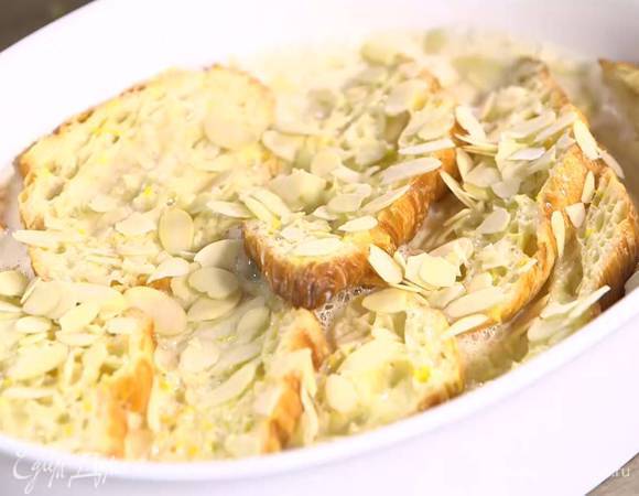 В жаропрочную керамическую форму выложить половинки круассанов срезами вверх, залить сливочной смесью и посыпать миндальными лепестками.