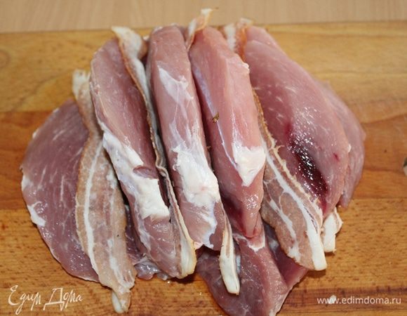 Мясо нарезать на дольки, не прорезая до конца, как книжку, в каждый разрез вложить по пластинке бекона. 