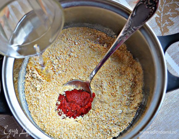 Томатную пасту «Помидорка» соедините с мукой, влейте около 150 мл горячей воды и тщательно перемешайте. Дайте постоять 15 мин.