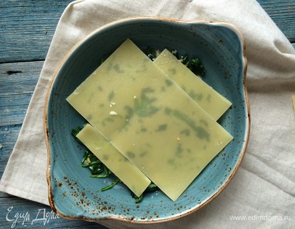 Положите на дно формы для запекания слой шпината и накройте его листами теста, затем выложите большую часть томатного соуса и потрите немного пармезана, накройте еще одним слоем теста. 