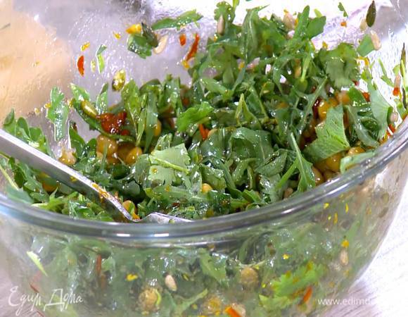 В заправку для салата выложить нут, подсолнечные и тыквенные семечки, руколу, нарезанную зелень и все перемешать.