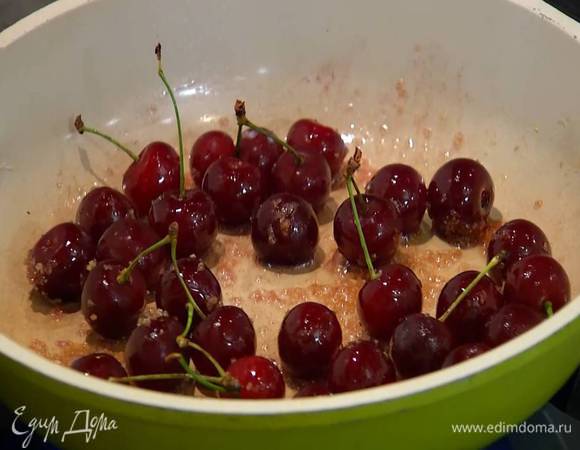 Растопить в сковороде сливочное масло, выложить в нее сахар и вишню на веточках и слегка припустить ягоды.