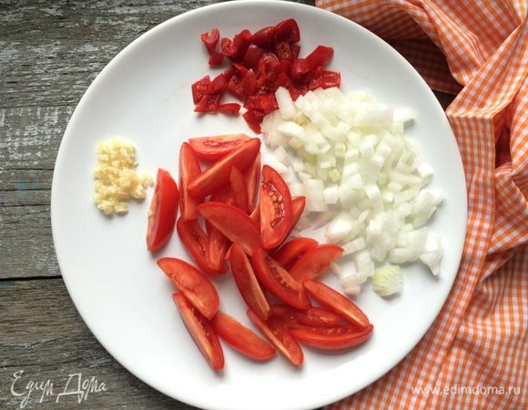 Тонко нарежьте 4 зубчика чеснока, перец и лук, затем разрежьте помидоры на 4-6 частей.