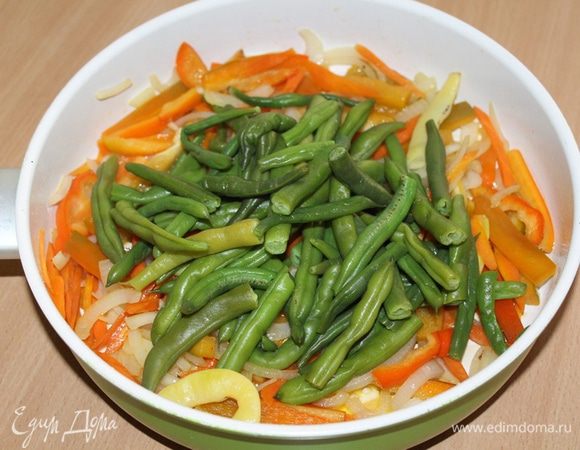 Вскипятить воду, подсолить воду и опустить нарезанную стручковую зеленую фасоль. Варить не больше 3 минут. Быстро откинуть фасоль на дуршлаг. Добавить к обжаренным овощам. Обжарить вместе 3 минуты.
