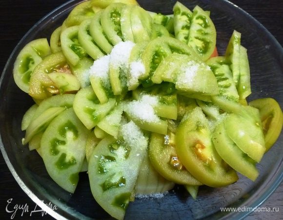 Зеленые помидоры вымоем, обсушим, разрежем пополам, а затем нарежем на тонкие полукольца. Посолим и оставим на полчаса. Выделившийся сок выливаем!