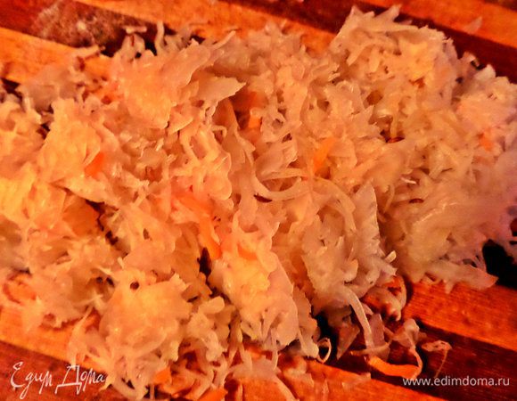 Капусту я для начала отжимаю, а затем нарезаю мельче. Рассол сливаю в стакан, потом может пригодиться или нет, если капуста достаточно кислая.