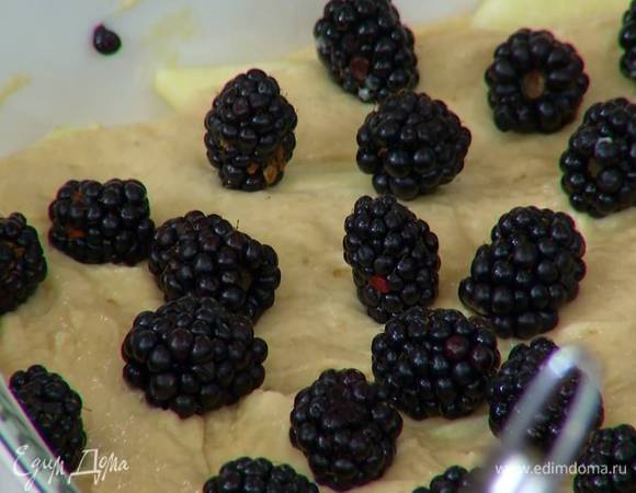 В жаропрочную керамическую форму выложить половину теста, в один слой разложить нарезанные яблоки, затем равномерно распределить оставшееся тесто, сверху выложить ежевику.