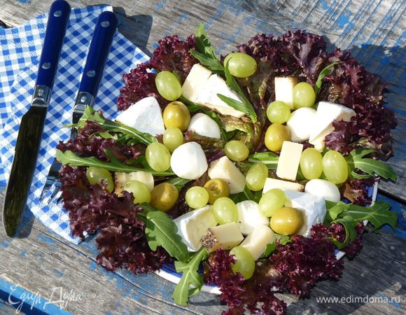 Листья салата выложить на тарелки, добавить руколу. Сыр нарезать брусками, бри — дольками. Выложить сверху салата, добавить моцареллу, виноград, орехи и оливки. 