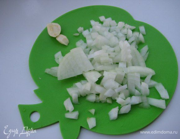 Лук мелко нарезать, зубчик чеснока раздавить плоской стороной ножа. В сотейнике разогреть оливковое масло, обжарить чеснок, затем его выкинуть. Добавить лук, на медленном огне потушить лук 10 минут, помешивая. Лук не должен зажариваться.