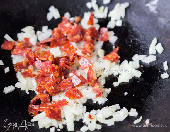 Когда лук станет прозрачным, добавить чоризо. Жарить все вместе пару минут, помешивая.