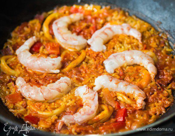 Выкладываем креветки по кругу в сковороду. Продолжаем готовить еще 5 минут. Через 5 минут вся вода должна впитаться в рис. Должно появиться небольшое шипение и потрескивание, потому что рис с низу должен немного поджариться.