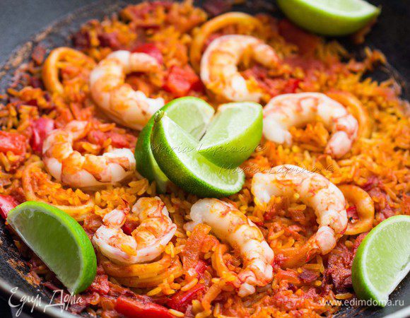 Чтобы рис не пригорел снизу, необходимо резко прекратить процесс готовки. Для этого смочите кухонное полотенце холодной водой, сверните его и поставьте на него сковороду. Накройте крышкой и дайте паэлье настояться 5 минут.
Паэлью можно поставить на стол прямо в сковороде, украсив ее ломтиками лайма или лимона.