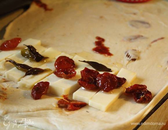 Каждую половинку теста раскатать примерно в 0,5–0,7 см толщиной. На половинку выложить моцареллу, помидоры и листочки базилика. Сложить, как вареник, и закрепить по краям.