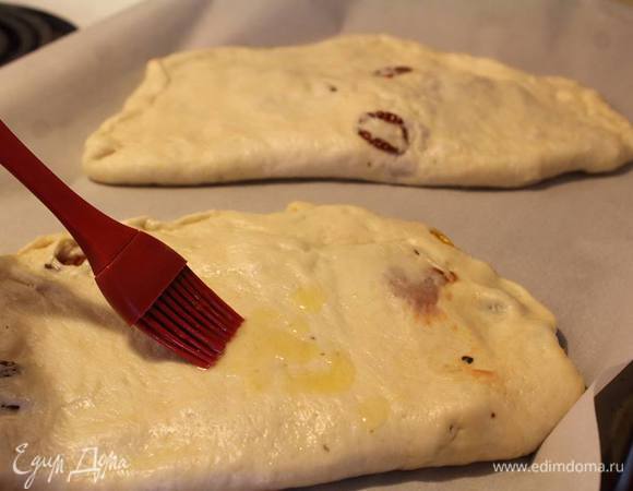 На противень, застеленый пекарской бумагой, выложить фокаччи и смазать слегка маслом.