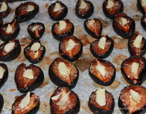 По истечении трех часов слива наша подвялилась, солим, перчим, посыпаем орегано и на каждую сливу выкладываем тоненькую пластинку чеснока. Отправляем в духовку еще на 1 час. Если у вас слива не очень крупная, то 4 часов вполне достаточно. У меня слива была крупная и мясистая, поэтому и на следующий день решила продолжить.