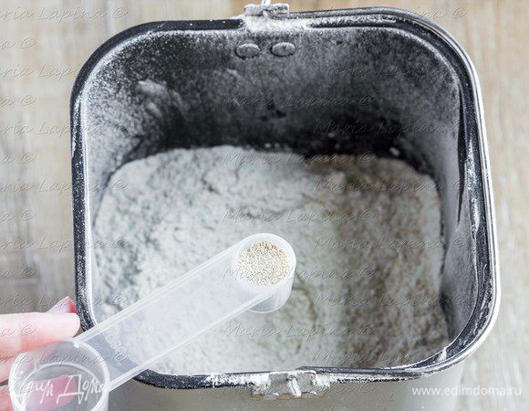 Всыпаем просеянную муку, в центр насыпаем дрожжи, по бокам — сахар и соль.