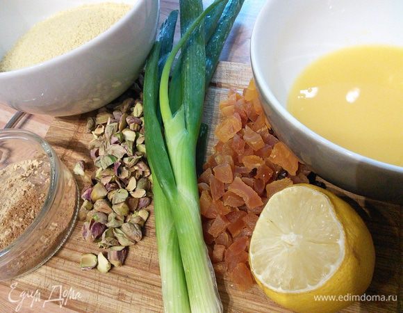 Подготовить продукты для кускуса. Курагу и инжир нарезать на кусочки, зеленый лук — колечками, фисташки крупно порубить. В пиалу влить апельсиновый сок, выдавить сок лимона. 
