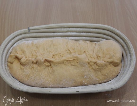 Уложите тесто в форму для расстойки, присыпанную мукой, уложив вверх швом.


