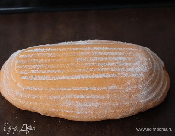 Тем временем разогрейте до 200°С духовку.
Аккуратно переверните подошедший хлеб на противень, застеленный пергаментом.


