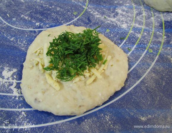 Каждый кусочек теста раскатать или придавить ладошкой, на середину положить натертый сыр и укроп.