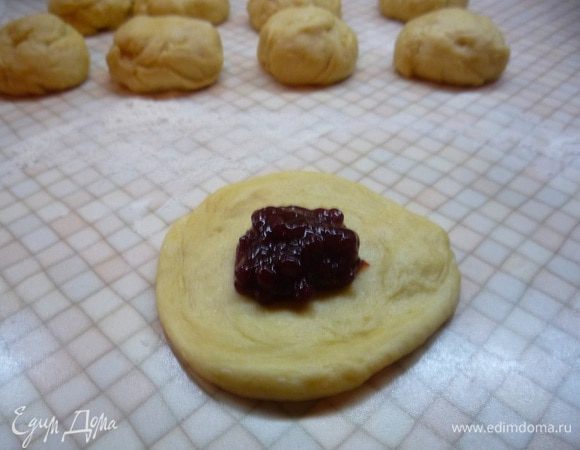 Каждый шарик расплющиваем руками в лепешку, укладываем в середину примерно 1 ч. л. начинки, соединяем все края в центре формируя круглую булочку.