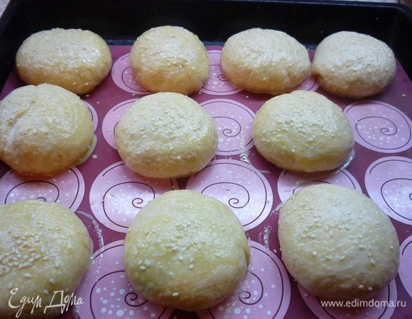 Булочки укладываем на слегка смазанный маслом противень (у меня силиконовый коврик) швом вниз. Оставляем булочки для расстойки на 30 — 40 минут, они должны увеличиться вдвое. По истечении этого времени смазываем булочки взбитым яйцом и посыпаем кунжутом.