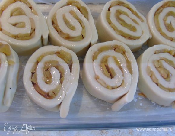 Форму смажьте маслом и выложите рулетики срезом вверх, но не плотно, поодаль друг от друга. Накройте полотенцем и дайте 15 минут подойти, а этим временем разогрейте духовку до 180°С.
