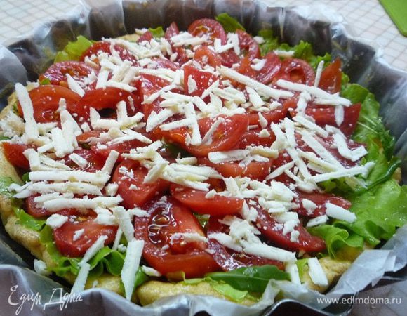 На листья салата укладываем нарезанные дольками помидоры и посыпаем крупно натертой овечьей брынзой. Убираем тарт в духовку еще на 10 минут.
