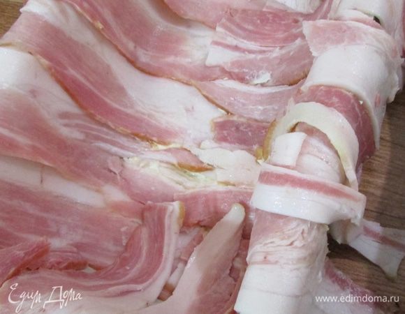 Поверх масла застелить беконом внахлест, оставляя свисающие края.