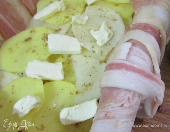 На бекон выложить картофель и присыпать слегка мускатным орехом. Положить несколько кусочков сливочного масла. Солить не нужно.